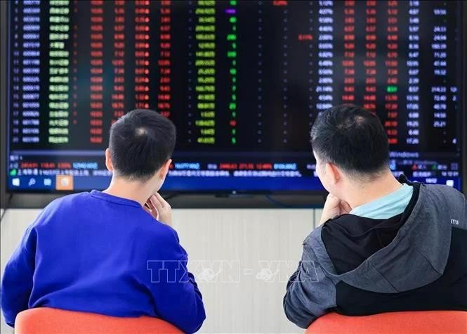 Nhà đầu tư theo dõi bảng chỉ số chứng khoán tại Trung Quốc. Ảnh: THX/TTXVN chung-khoan.jpg